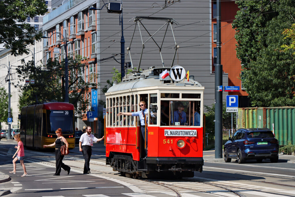 Tramwaj linii W. Przy drzwiach widoczni konduktorzy dający sygnał gotowości do ruszenia z przystanku.